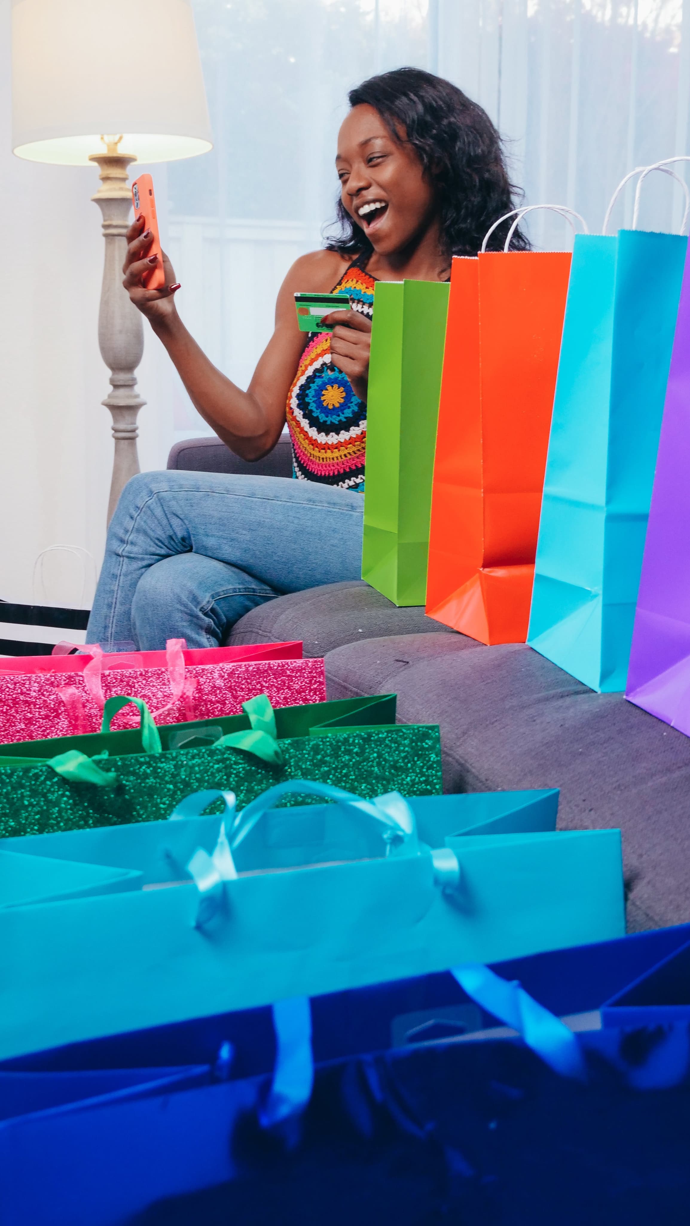 remark - woman looking at her phone and smiling with colorful shopping bags beside